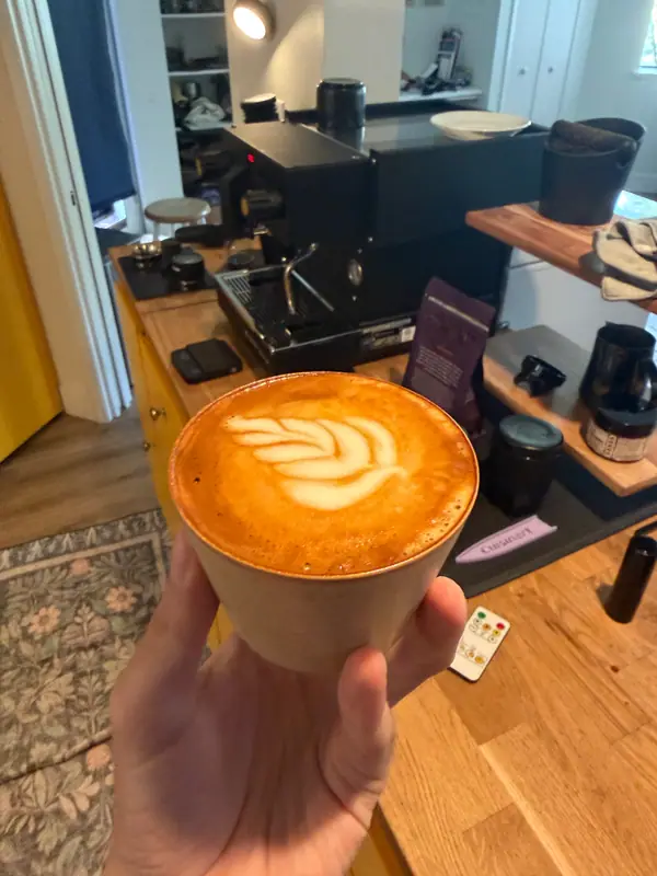 A latte with rosetta art held up in front of the espresso machine