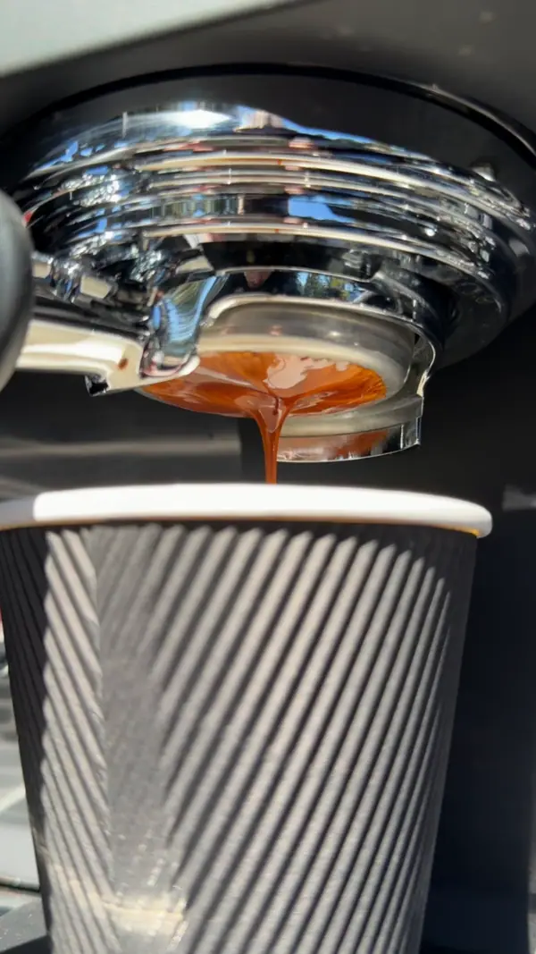 Espresso pouring into a striped paper cup