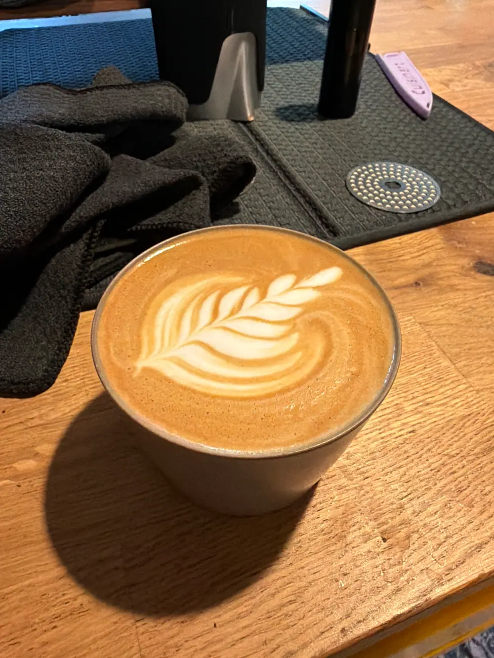 A latte with rosetta latte art on a wood counter